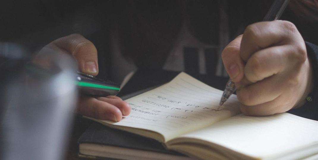 student taking notes and using a calculator